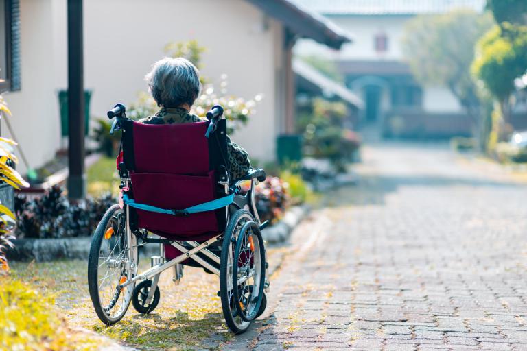 A lady in a wheelchair seen from behind with buildings in the background