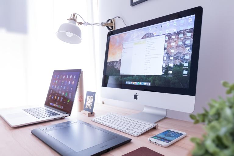 Apple computer, desktop, phone and iPad on a desk with plant