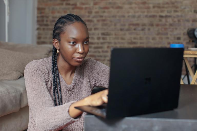 Female student with braids looking at a laptop