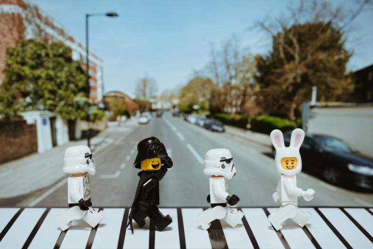Lego figures crossing the road in the style of a Beatles album cover.