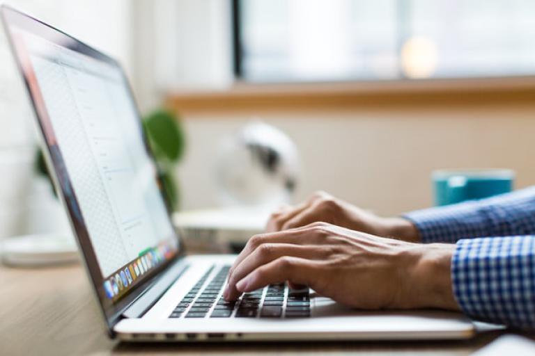 Hands typing on a laptop.