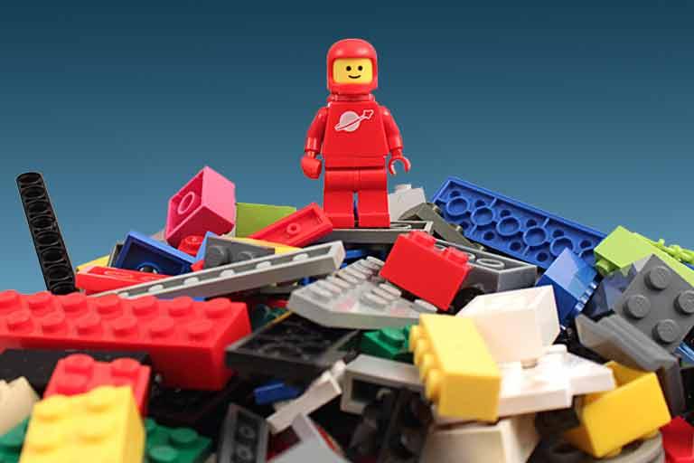 Lego minifigure astronaut climbing a mountain of Lego.