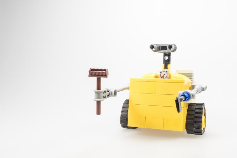Lego model of Wall-E holding a broom.