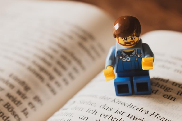 Lego man standing on an open book.