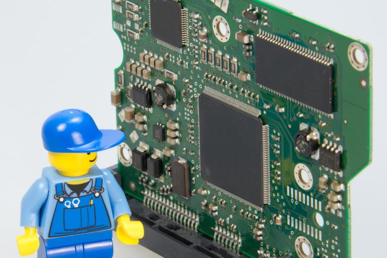 Lego minifigure next to electronic chip board.