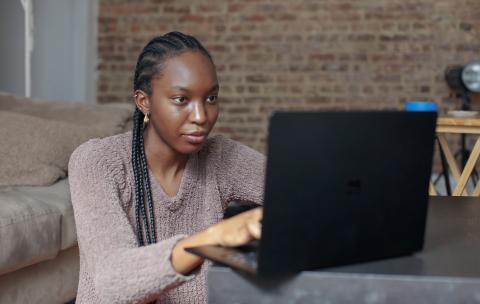 Female student with braids looking at a laptop